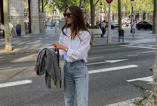 Woman wearing a white button-down and jeans.