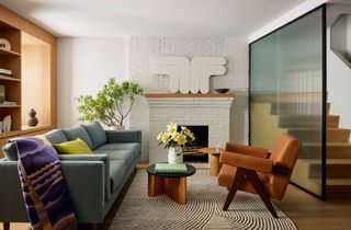 a living room with a white brick painted wall, a light blue sofa, and a curved rug