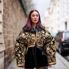 Heart Evangelista wears a black and gold oversized jacket, a black velvet mini skirt