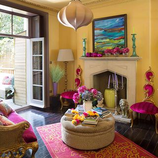 living area with yellow wall and fire place and pink chairs and wooden floor