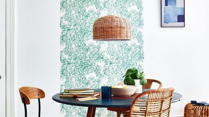 White dining room with strip of green patterned wallpaper leading up and onto ceiling 