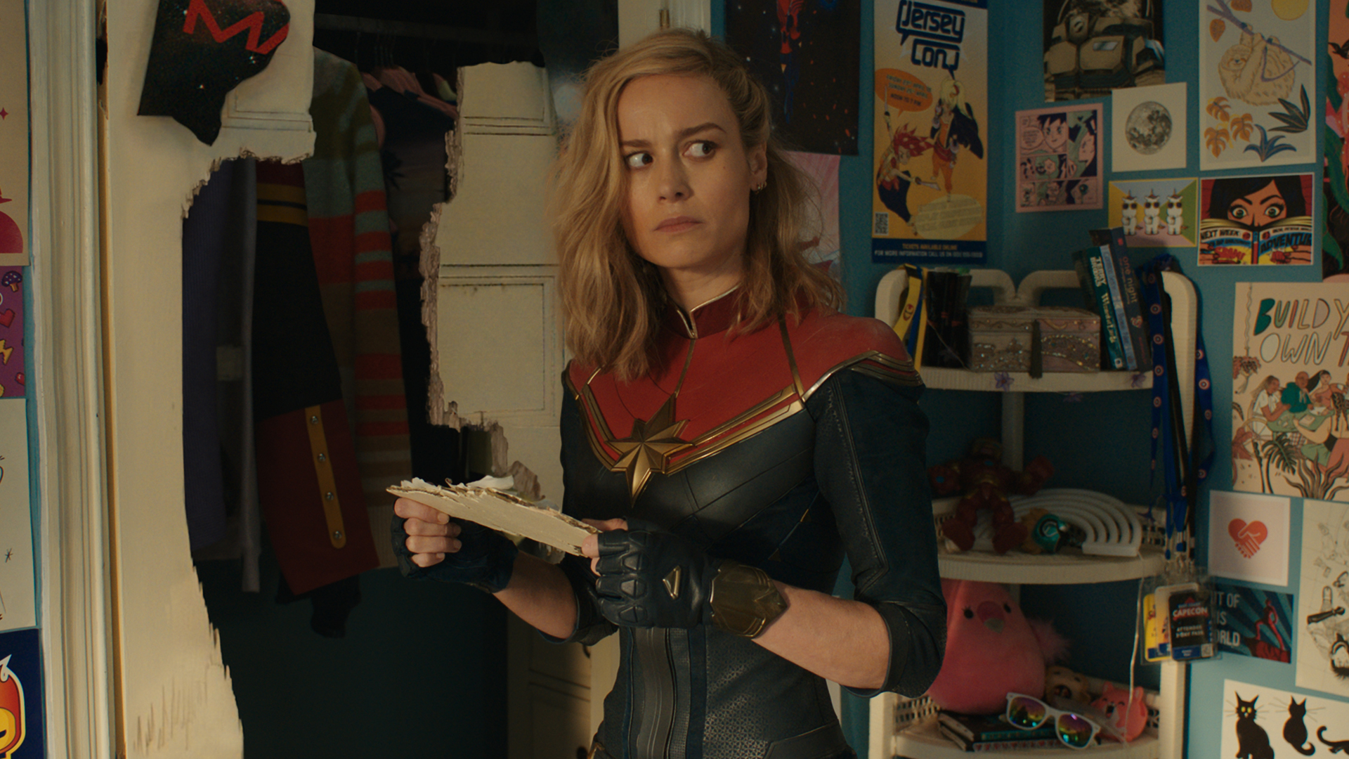 Captain Marvel looks puzzled as she stands in Kamala Khan's room in The Marvels