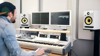 Producer in the studio flanker by a pair of white KRK Rokit RP5 G4 speaker