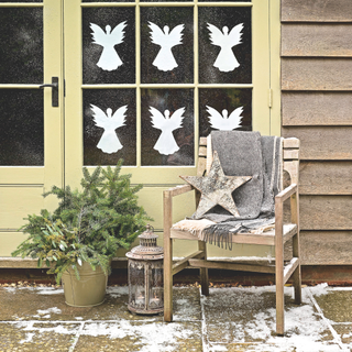 Rust front porch, French windows, paper angels decorating windows, wooden garden chair, unusual birch wood star, vintage lantern, bucket of pine sprigs