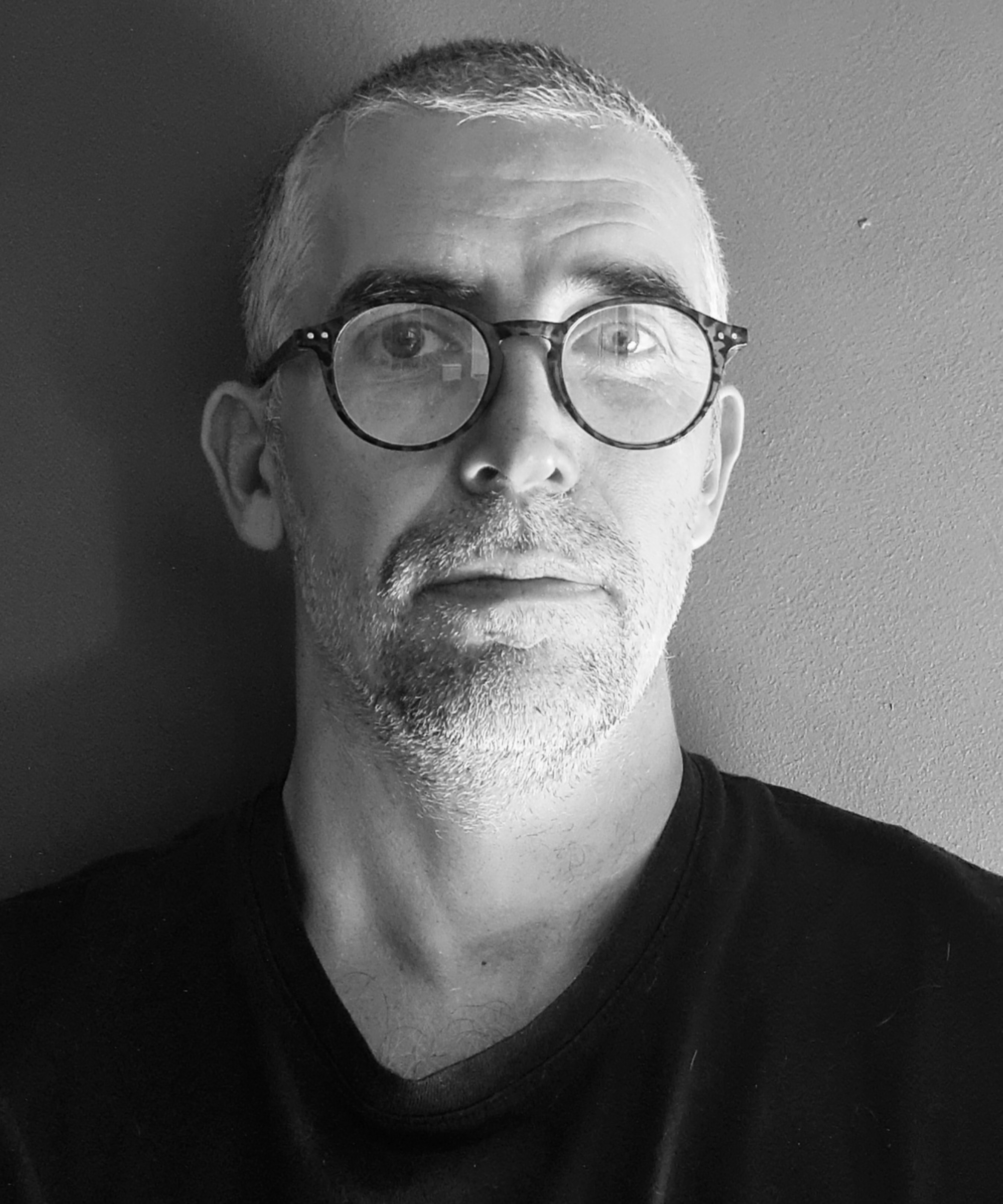 black and white headshot of man with short hair, beard and glasses