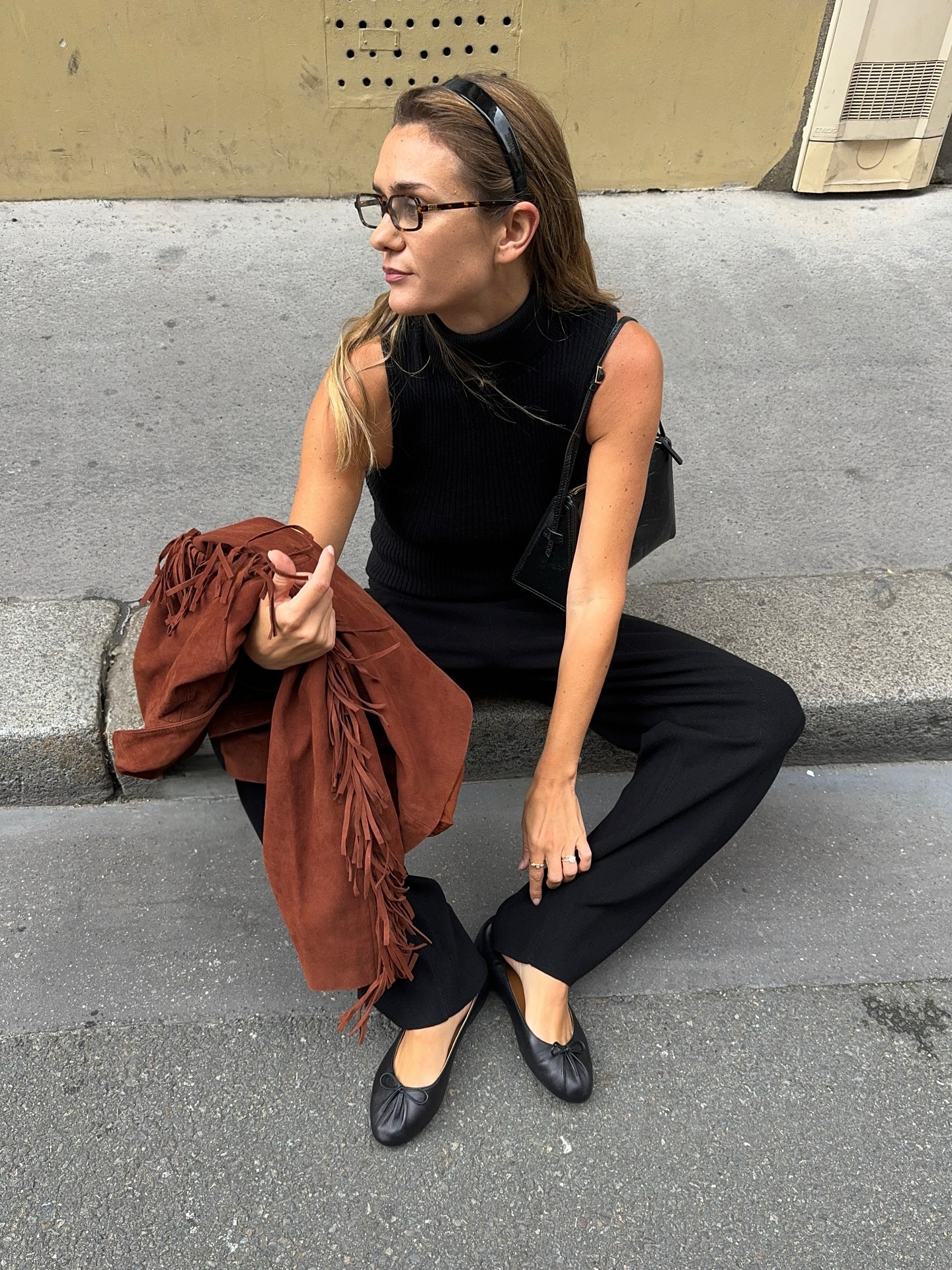 @annelauremais wearing a black sleeveless top, black trousers, and ballet flats.