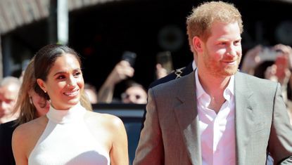 Meghan Markle and Prince Harry enter the invictus games in beige outfits including a white tank top and belted khaki pants