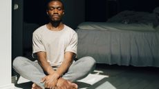 Man sat on the floor of a bedroom meditating