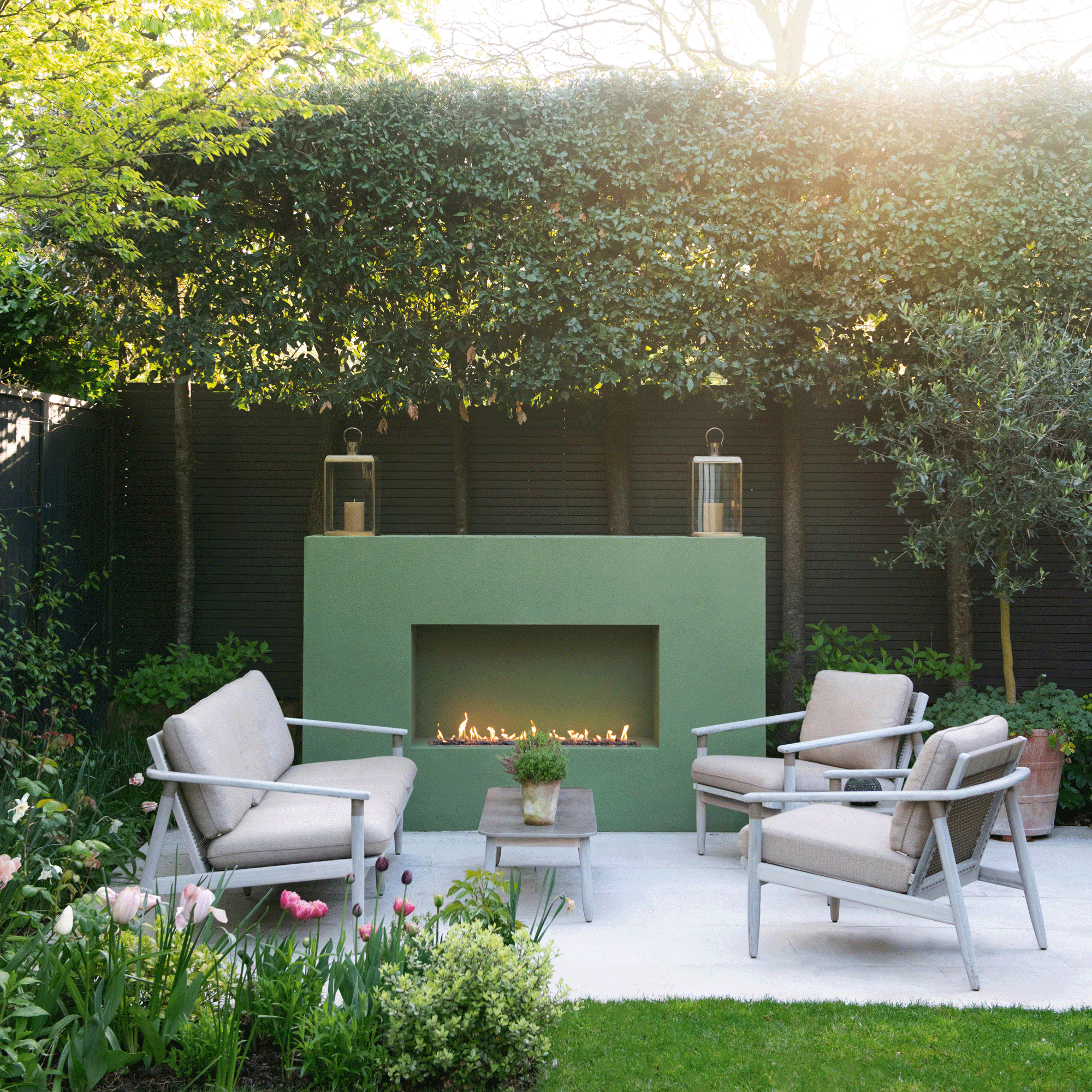 a garden with a patio area and large green outdoor fireplace and seating in front