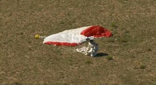 Felix Baumgartner kneels on the ground after landing safely from the highest skydive ever.