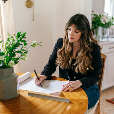 picture of interior designer Lauren Saab sitting at a table sketching 