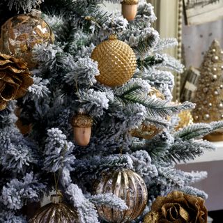 Decorated snow covered Christmas tree with gold baubles