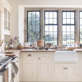 country kitchen with cream cabinetry and walls with white aga and stone mullion windows