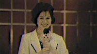 A woman with a microphone in a blurry picture.