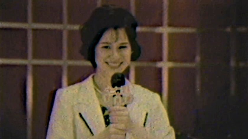A woman with a microphone in a blurry picture.