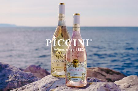 Two bottles of wine, white and ros&eacute;, on a rock with sea in the background, and 'Piccini' written in white over the top