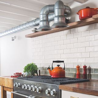 industrial kitchen with exposed ducting extractor and orange kettle