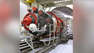 A red and black cylindrical spacecraft being prepared for launch