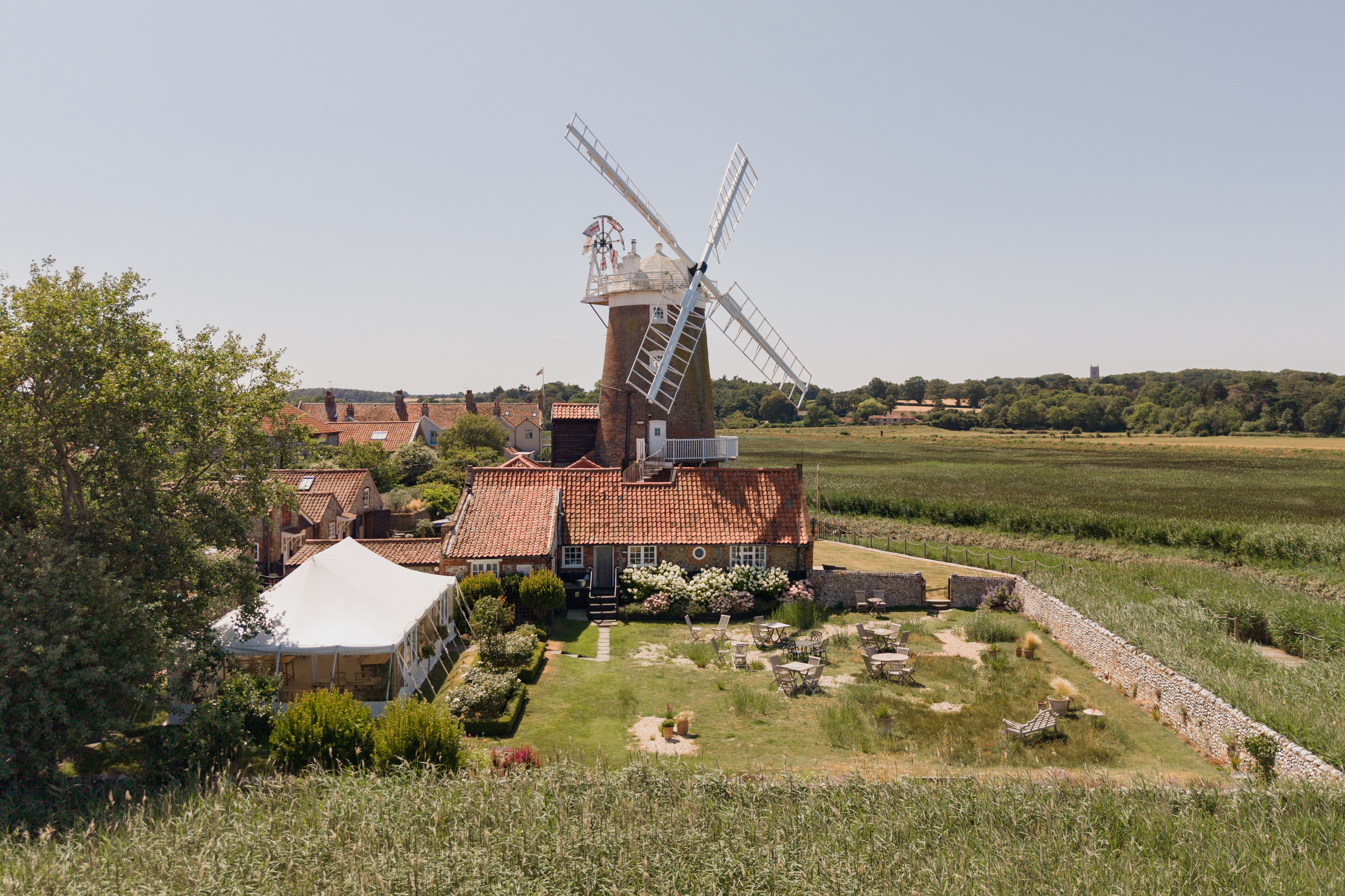 Cley Windmill. The mill is surrounded by reed beds and little rivers, and it is red brick with a white top. Inside, the rooms are luxurious but rustic, with lots of brick and exposed beams.