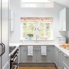 galley kitchen with white kitchen cabinets with pink floral blinds