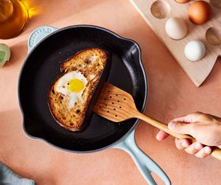 Eggy bread in a Le Creuset skillet against a peach background.