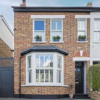 exterior of brick house with bay window and black front door