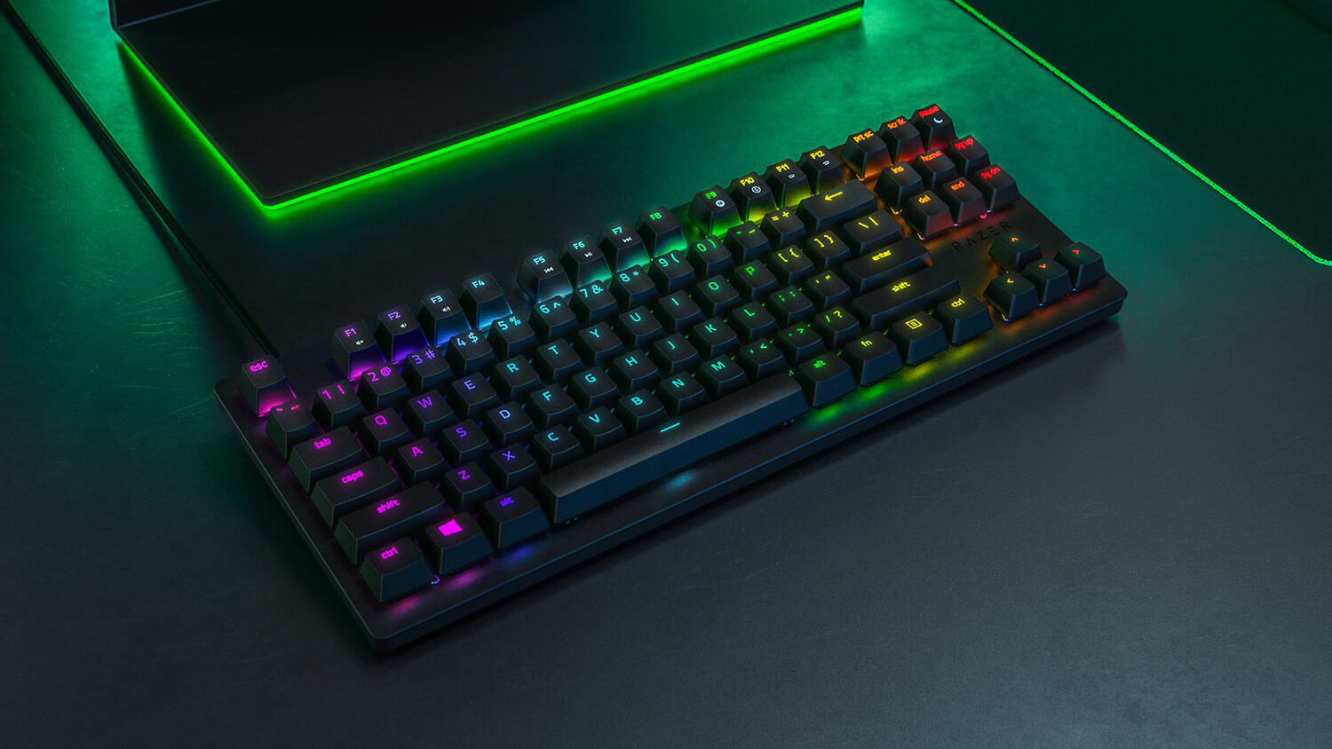 Ett Razer Huntsman Tournament Edition-tangentbord ligger på en mörk yta och lyser i olika RGB-färger.