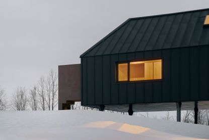Silver Heights, a black, Ontario cabin house among snow