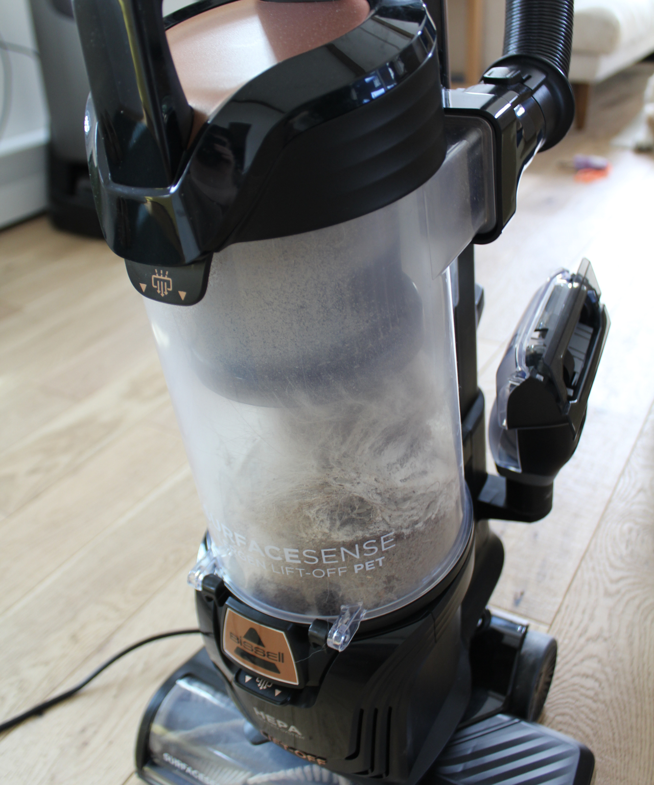 Closeup of the Bissell SurfaceSense Allergen Pet Lift-Off Upright Vacuum dustbin partially filled with dust and hair in Camryn Rabideau's home