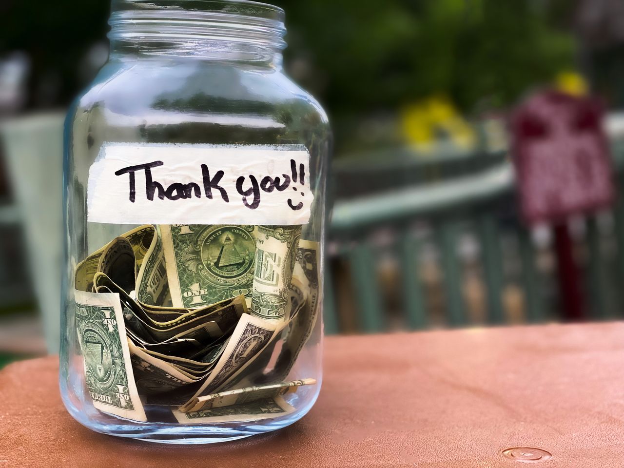 Glass tip jar at checkout counter with cash. 