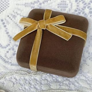 a mustard velvet ribbon tied in a bow around a brown velvet box