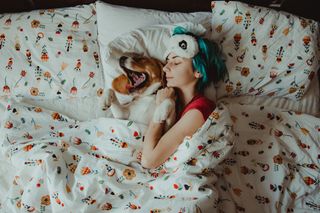 High Angle View Of Woman Relaxing On Bed At Home With Dog
