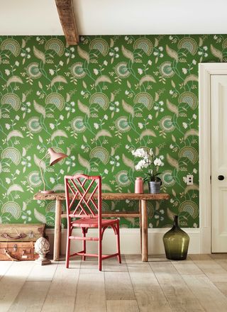 leafy wallpaper in a home office with coral desk chair