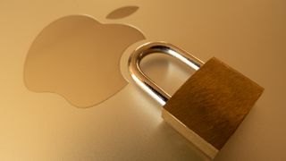 A golden padlock and key resting in the Apple logo