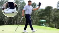 Bryson DeChambeau waves to the crowd whilst walking off the putting green