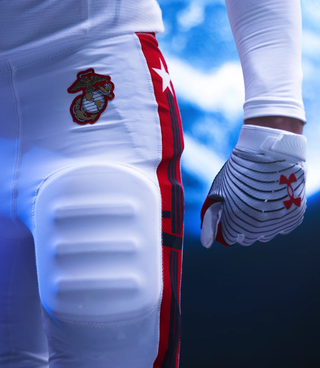 white padded pants with a red stripe down the outer leg and the navy's logo