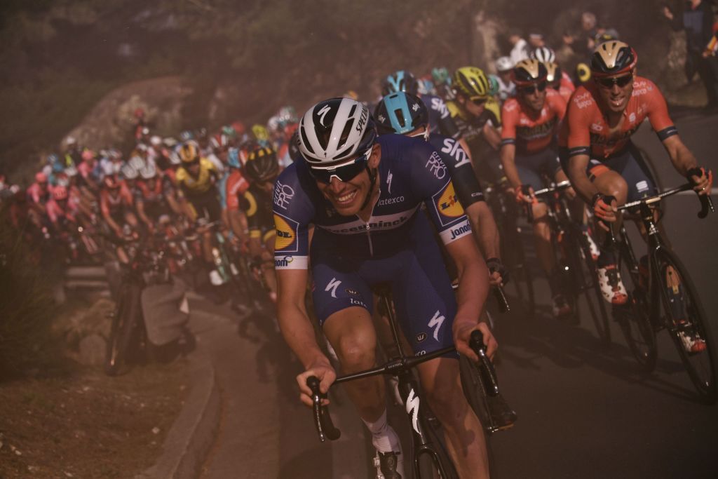 Tim Declercq leads the peloton through some flare smoke on the Capo Berta
