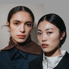 two women with glowing skin and lip stains wearing navy blue outfits
