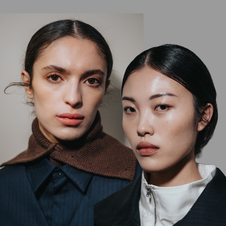 two women with glowing skin and lip stains wearing navy blue outfits