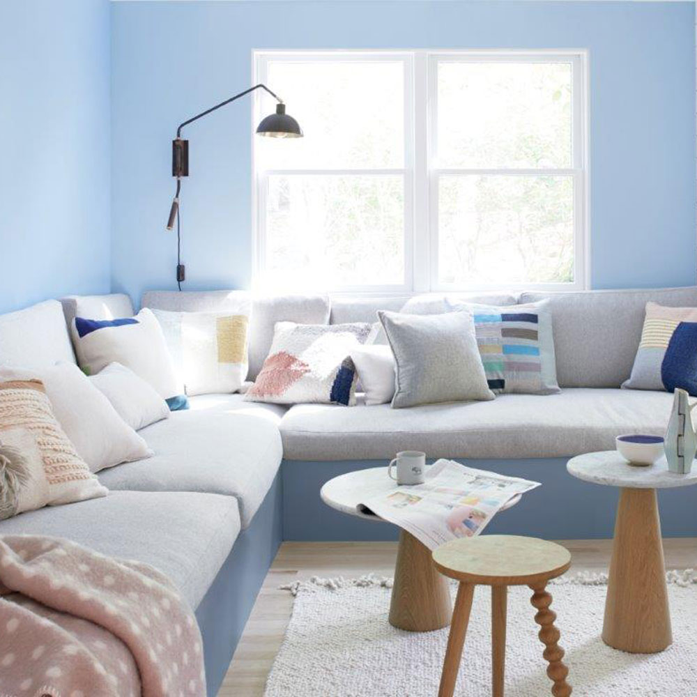 Pastel blue living room with grey and blue sofa and a big window