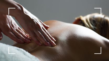 Woman lying down on a massage table having a back massage with therapist's fingers on her back, after finding out how often should you get a massage