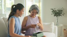 A picture of two women smiling at a smartwatch that was gifted by one to the other