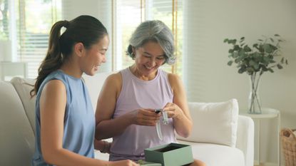 A picture of two women smiling at a smartwatch that was gifted by one to the other