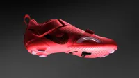 A single red Nike SuperRep Cycle shoe floating in front of a darkened background