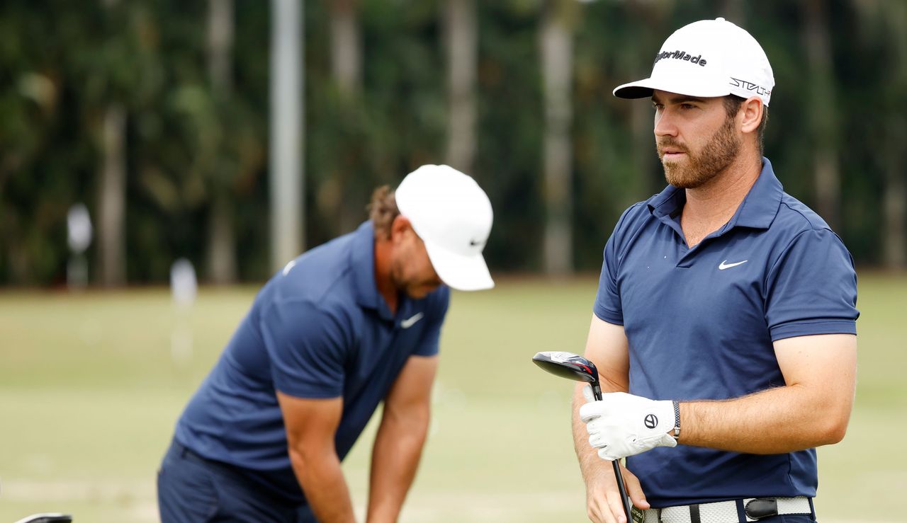 Brooks Koepka hits a golf ball whilst Matt Wolff walks off the range