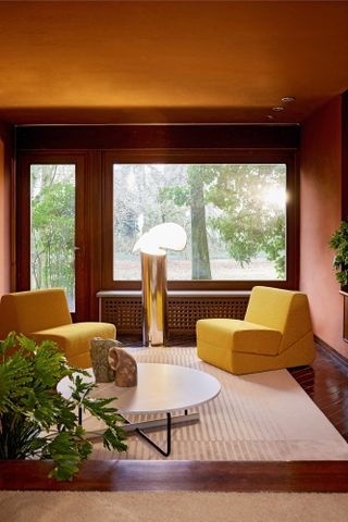 A warm-toned living room featuring a Flos Chiara floor lamp