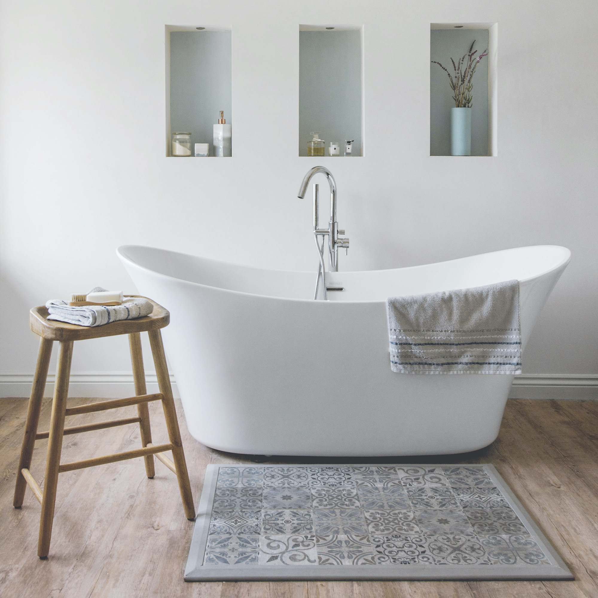 white bath with wooden flooring and wood stool grey mat