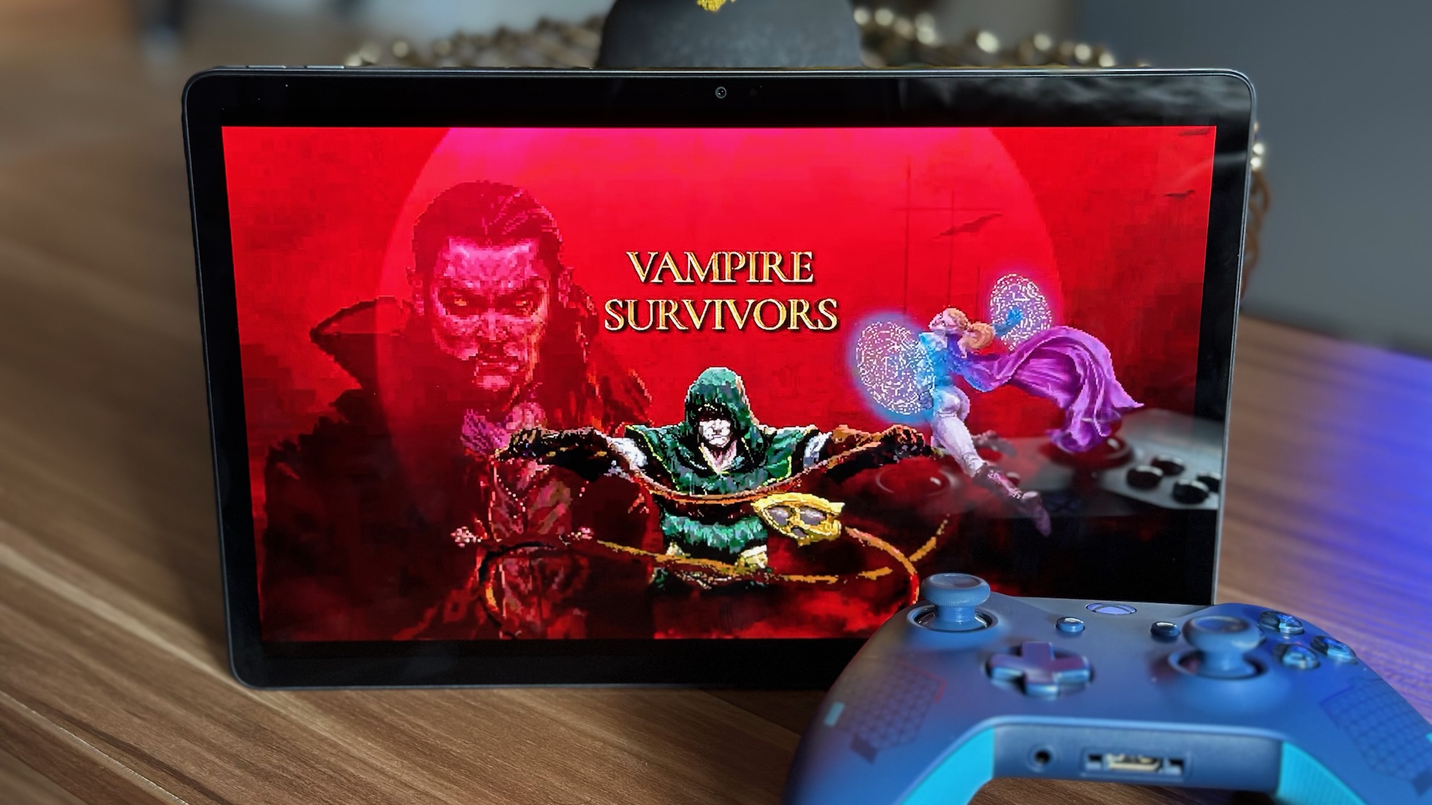 The Vampire Survivors start screen on the Lenovo Tab P11 Pro (2nd Gen), with an Xbox controller in front of the tablet.