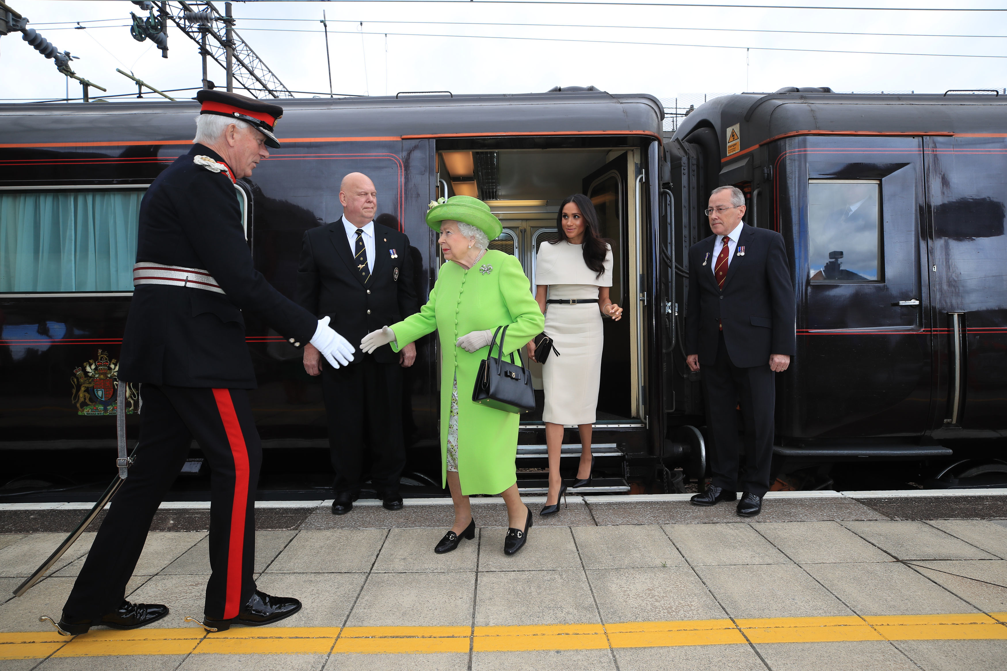 Meghan Markle wears a cream dress and attends a joint engagement with Queen Elizabeth, who wears a bright green coat, on June 14, 2018