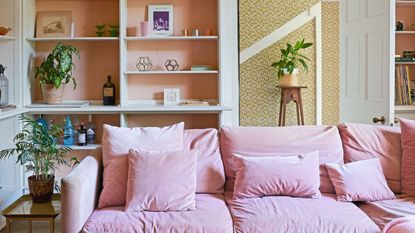 Living room with built in shelving and decorative furnishings, large pink L-shaped sofa
